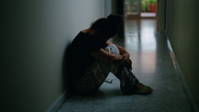 Middle age hispanic woman suffering for domestic violence with bruise on eyes sitting on floor at home